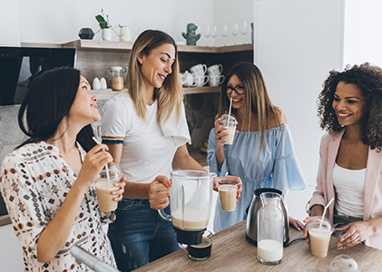 Grupo de mujeres preparando y consumiendo batidos lácteos